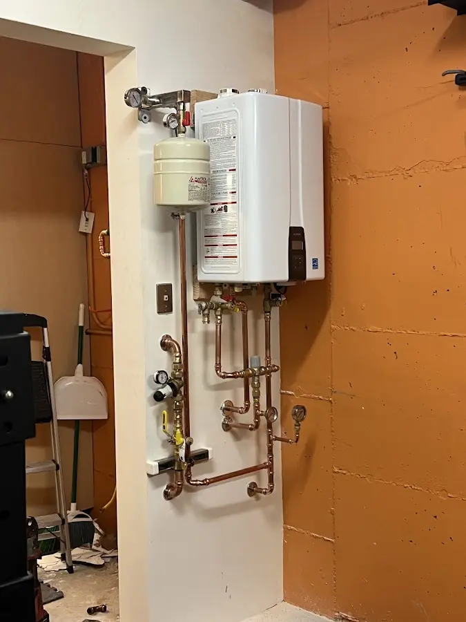 Plumbing technician inspecting water heater connections in Pomfret